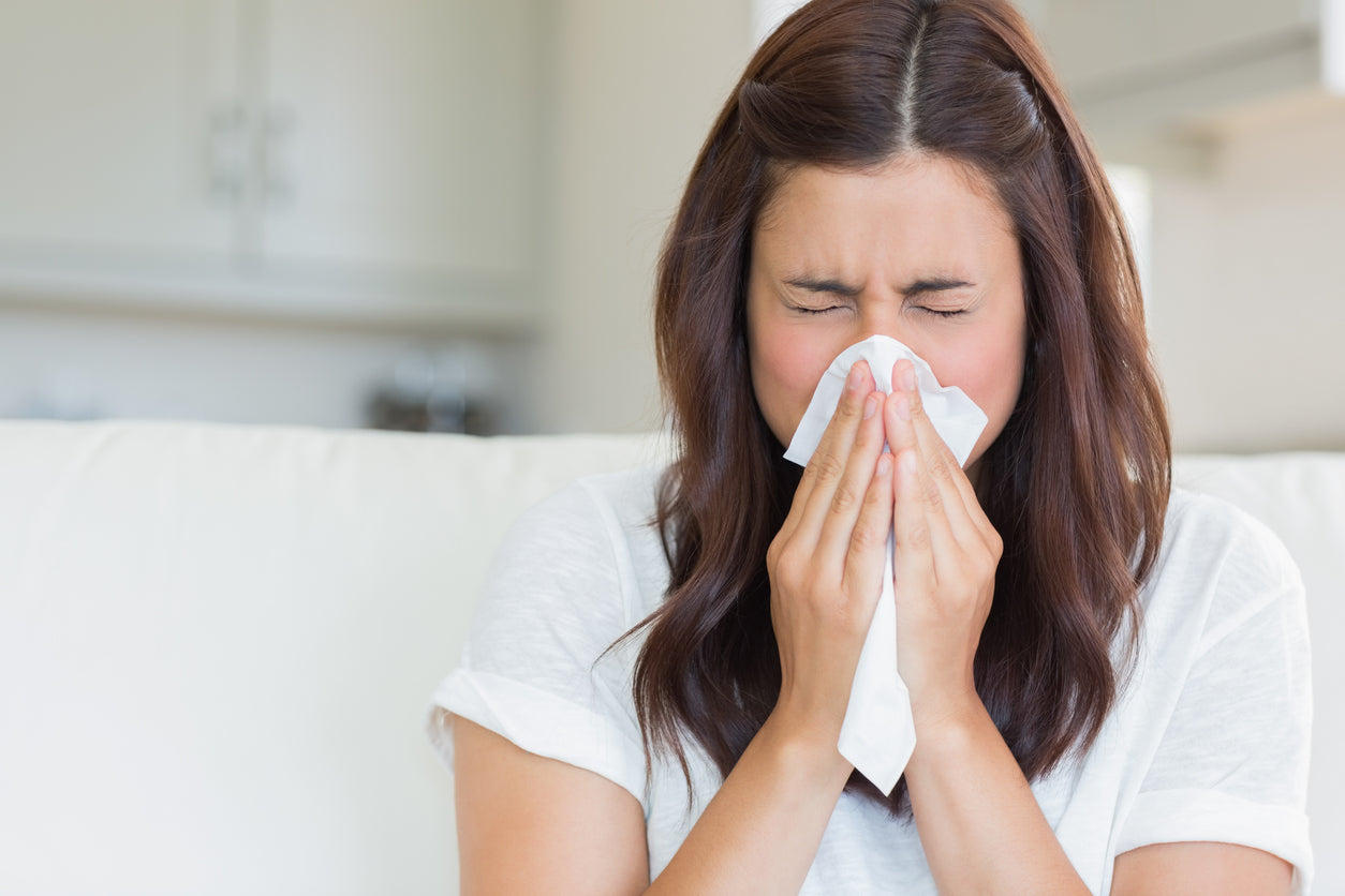 Femme en train de se moucher avec un système immunitaire affaibli.