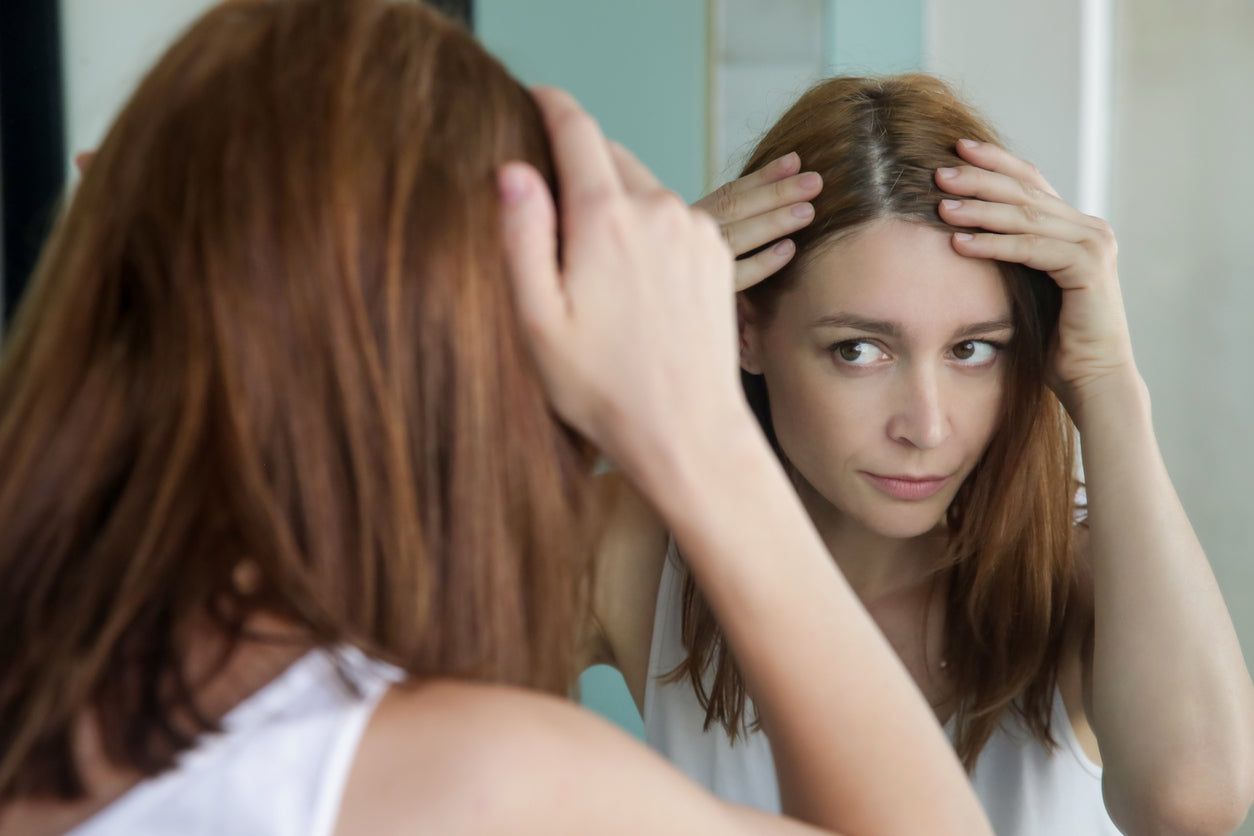 Femme constatant une perte de cheveux progressive, due à l’alopécie.