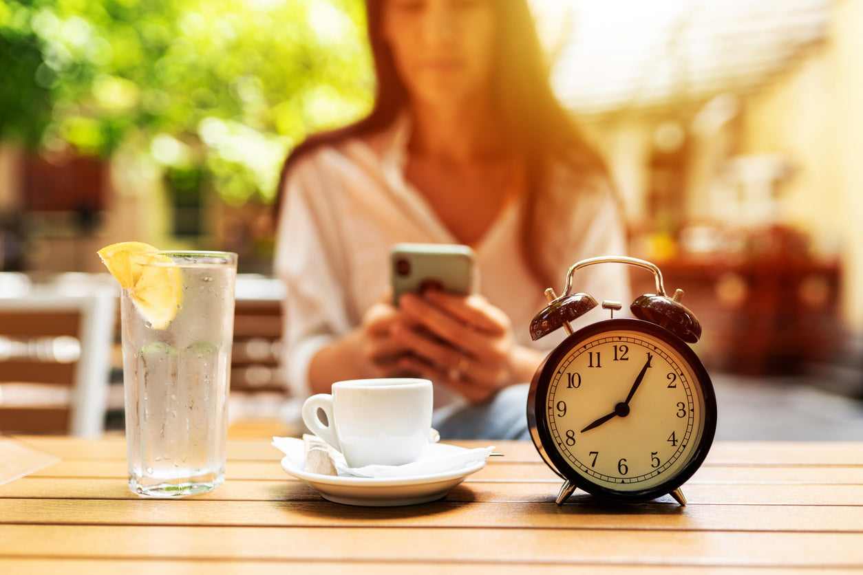 Jeune femme attablée devant une horloge, et ayant adopté un régime basé autour des principes de la chrononutrition.