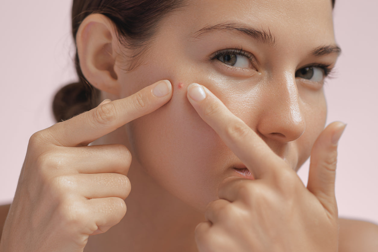 Jeune femme qui regarde sa peau grasse et qui tente de la rendre moins grasse.